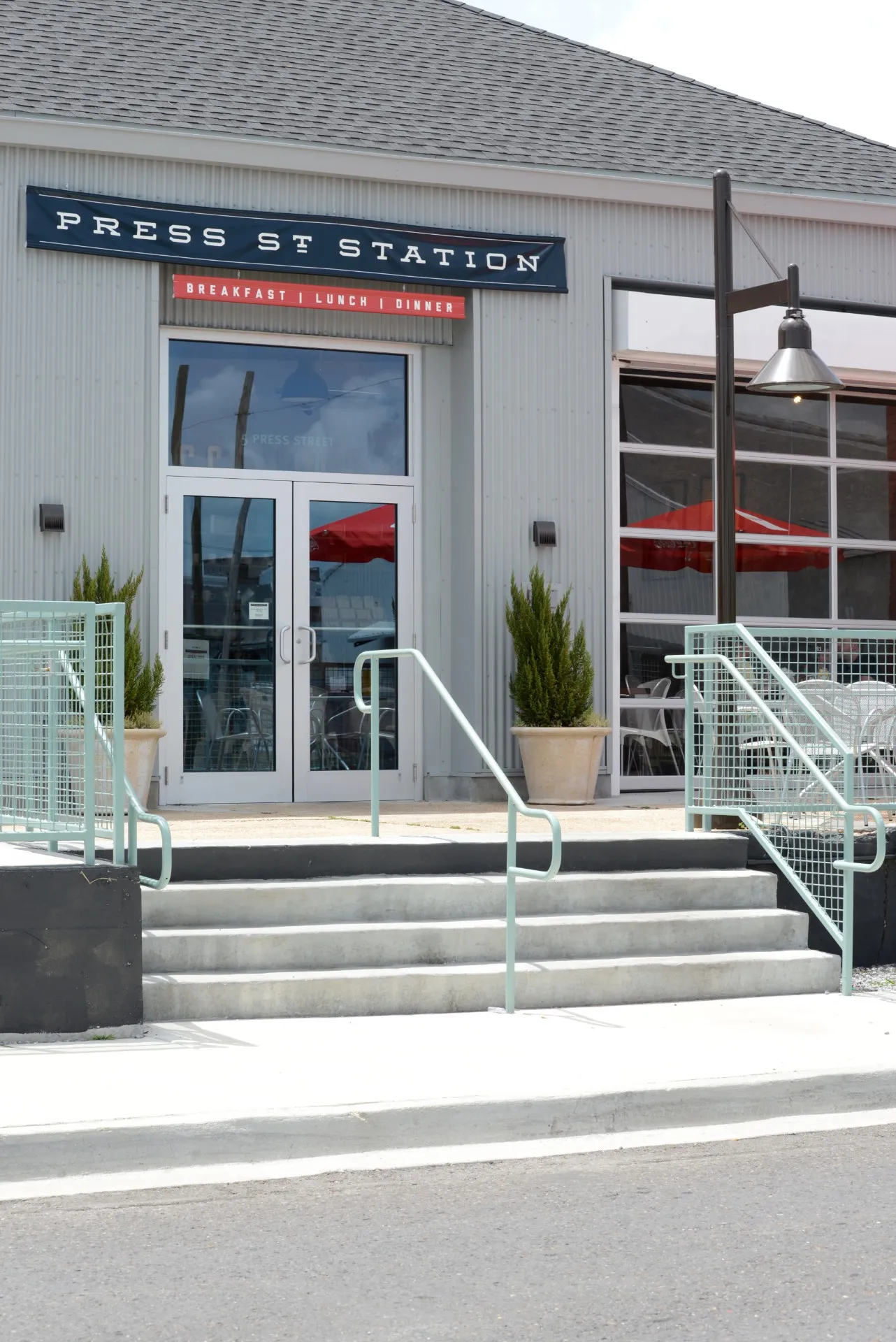 Front entrance of Press Street Station, a modern New Orleans event venue with patio seating and industrial-style design